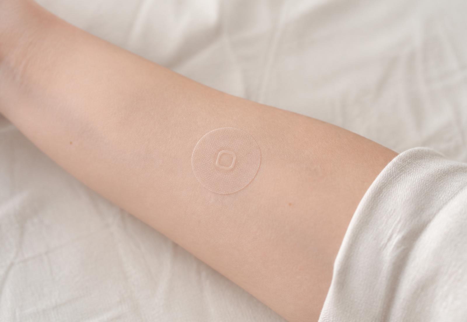 A thin translucent Cardinal patch applied to the inner forearm in soft daylight